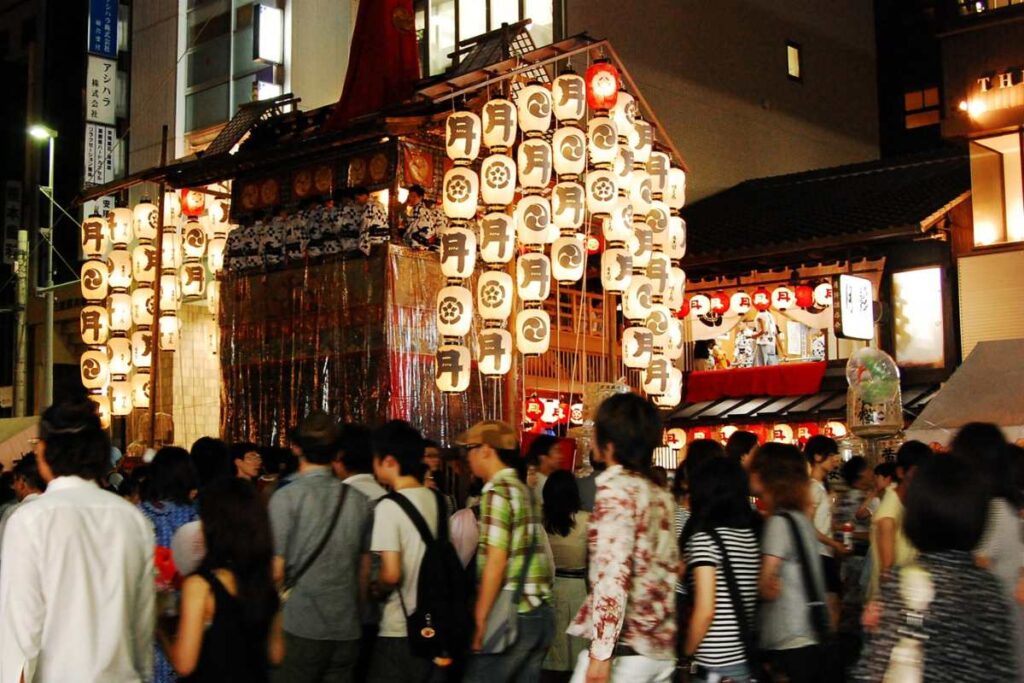 Crowds enjoying the Yoiyama night festival as a lantern-lit float stands on display during Gion Matsuri in Kyoto.