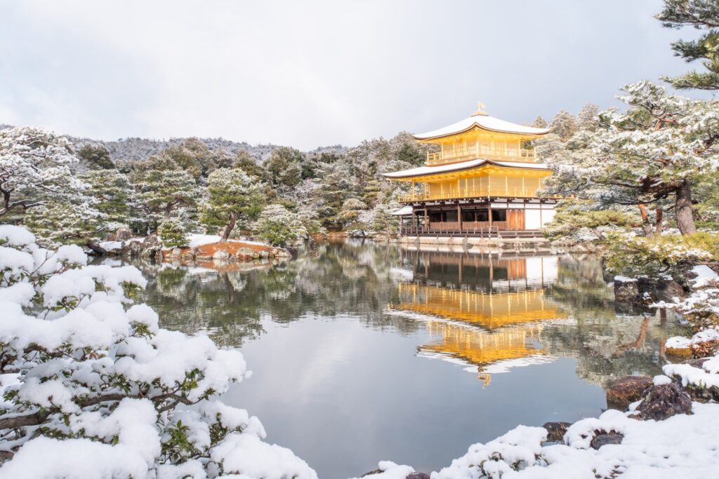 Kinkaku-ji temple covered in snow, reflecting beautifully on the still pond in winter