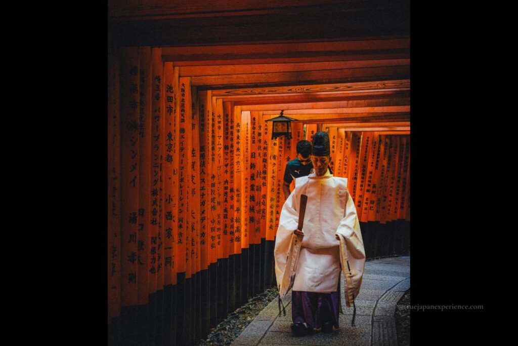 Shinto priest walking through the torii gates of Fushimi Inari Shrine in Kyoto