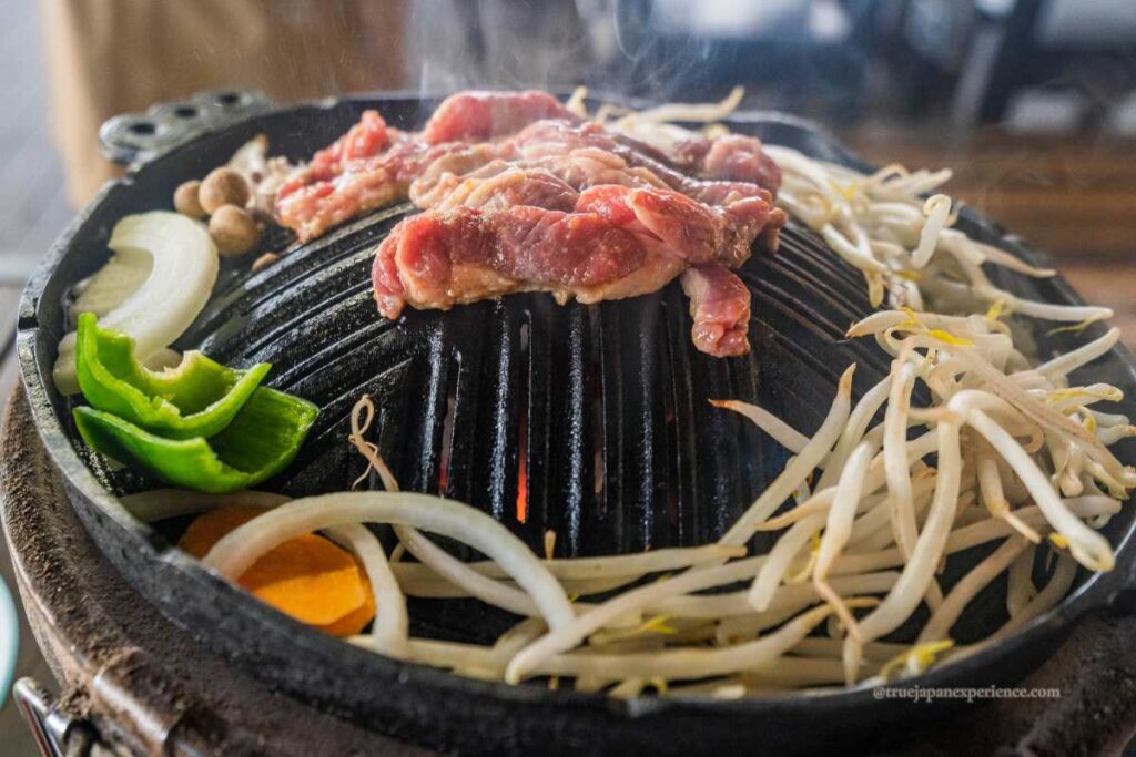Grilled lamb and vegetables on a traditional jingisukan grill in Hokkaido