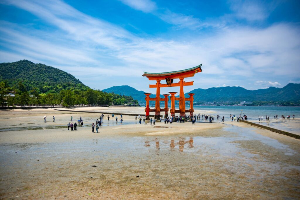 Tourists walking out to the floating torii gate of Itsukushima Shrine at low tide