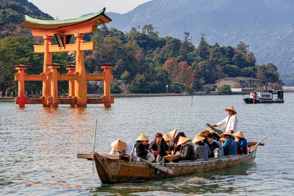 Tourists in a traditional boat tour near the floating torii gate of Itsukushima Shrine