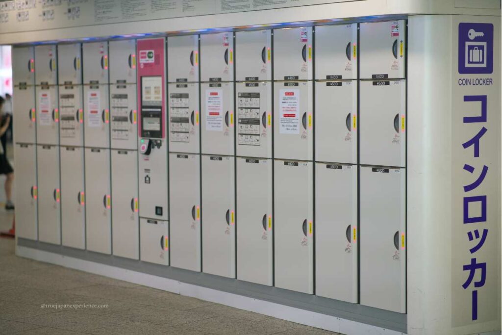A row of coin lockers in Japan with multilingual signage and a payment machine.