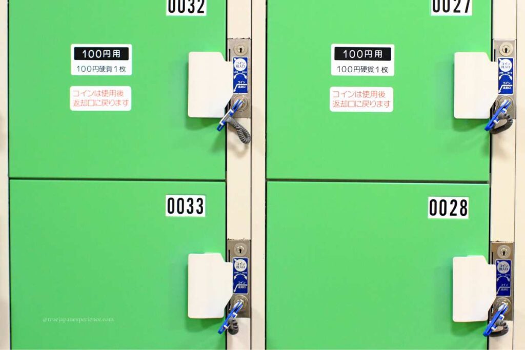 Green coin lockers in Japan with key locks and 100 yen usage labels.