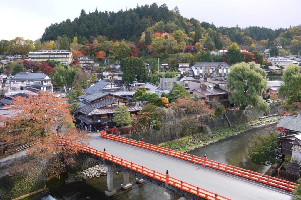 View of Nakabashi Bridge and the old town of Takayama, with autumn leaves and riverside homes.