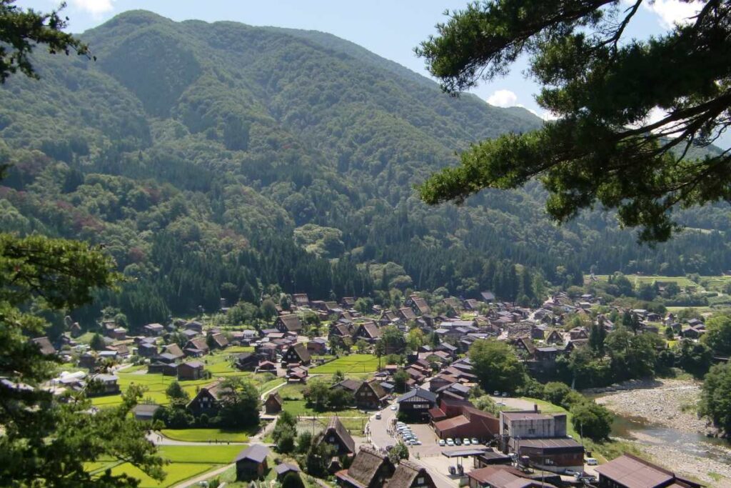 Panoramic view of Shirakawa-go from the observation point, surrounded by mountains and rice fields.