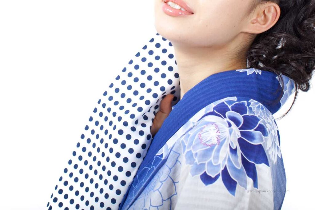 Woman in yukata holding a polka dot tenugui towel, often used during Japanese summer festivals.
