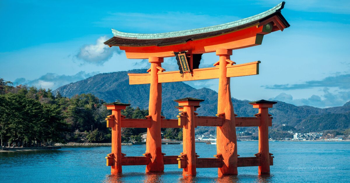 The floating torii gate of Itsukushima Shrine in the sea, with mountains in the background
