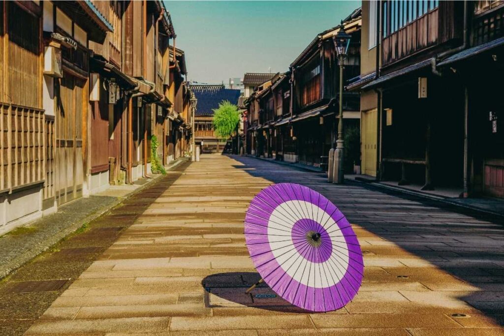 A purple traditional umbrella placed on a quiet stone-paved street in Kanazawa’s Higashi Chaya District