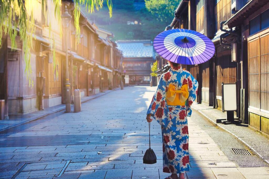 Woman in colorful kimono walking through Kanazawa’s historic teahouse district with a traditional parasol