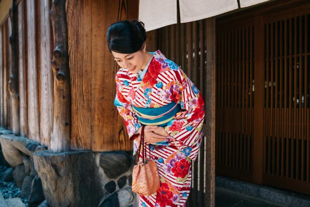 Woman in kimono gracefully bowing in a traditional Japanese street setting