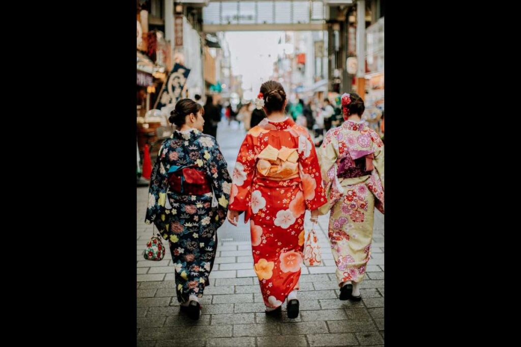 hree women in colorful kimono walking through a traditional covered shopping street in Japan