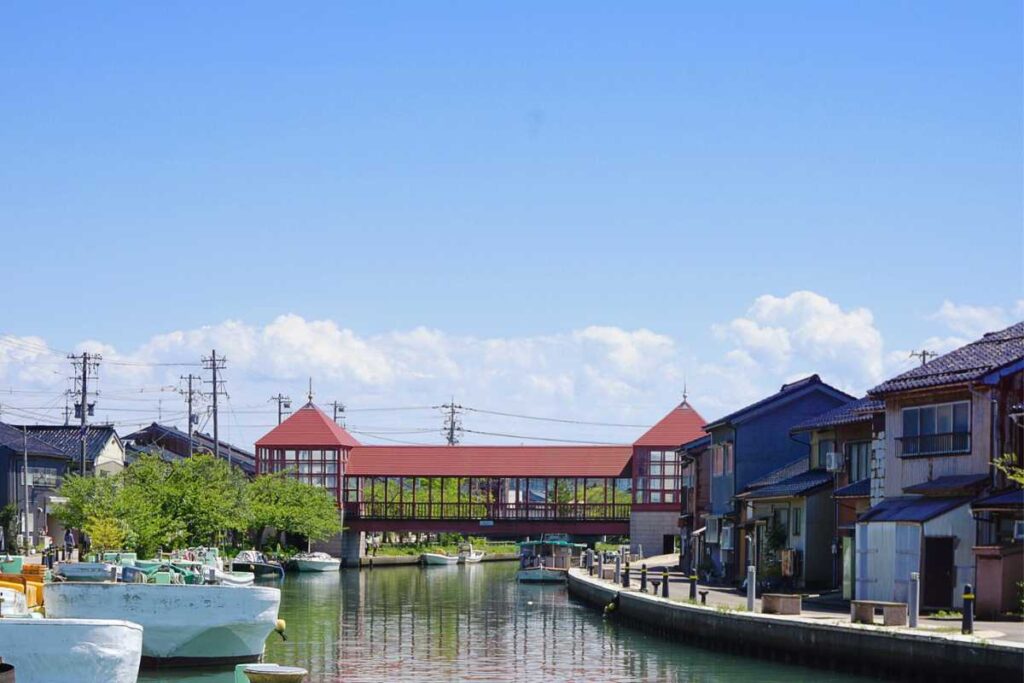 A peaceful canal scene in Uchikawa, Toyama — often called the “Venice of Japan” — featuring the iconic red-roofed bridge