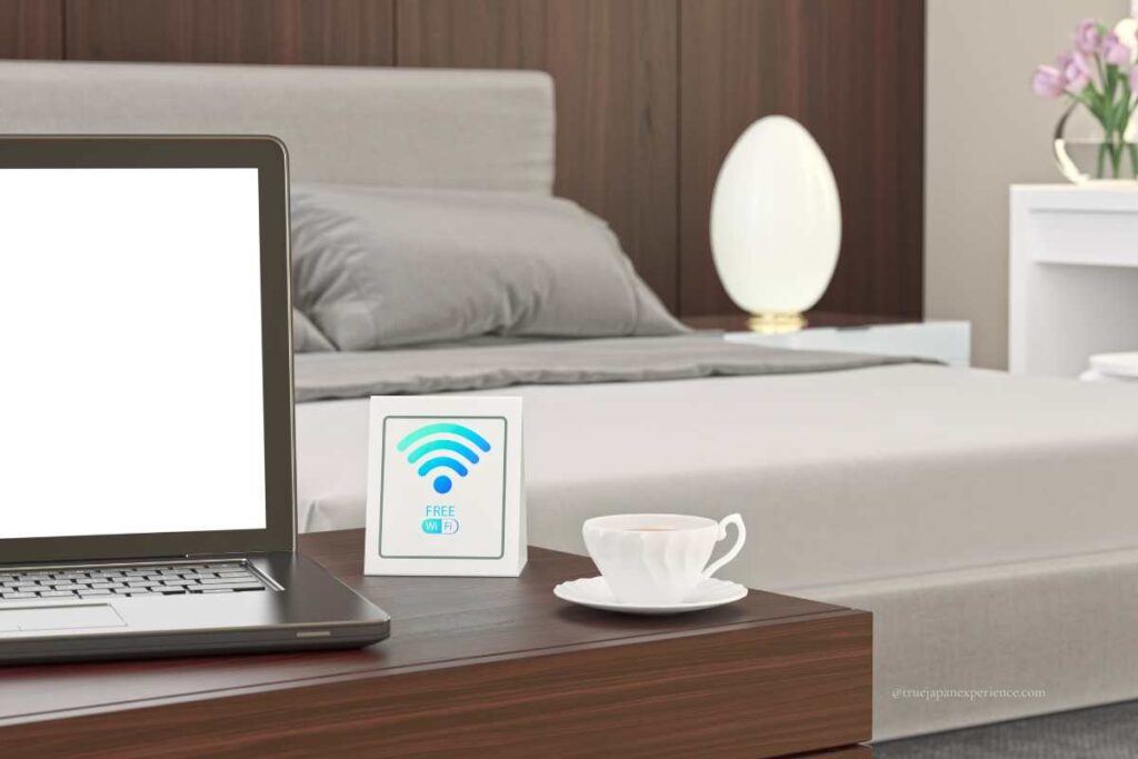 Free Wi-Fi sign next to a laptop and coffee cup in a hotel room