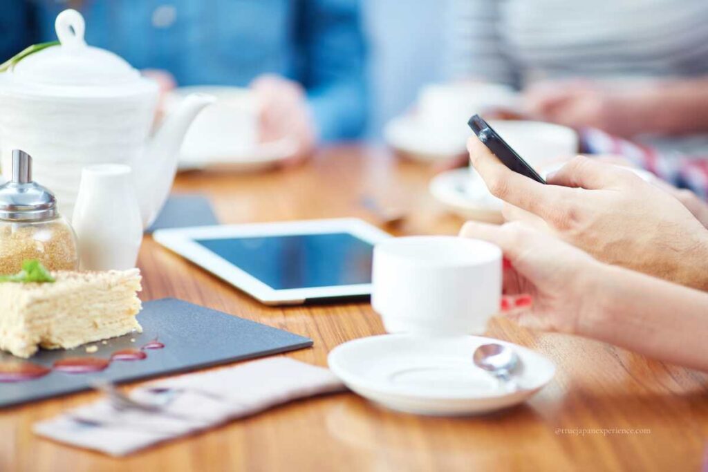 Person using a smartphone in a café with coffee and dessert on the table