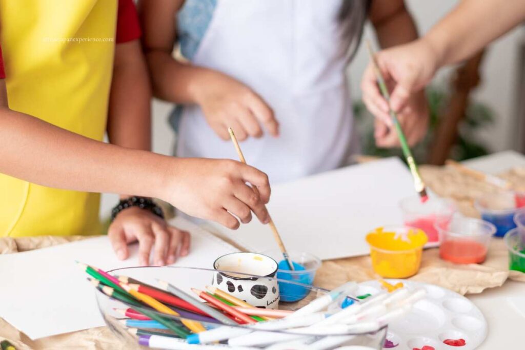 Children painting with brushes and colorful paints, enjoying a creative art activity together at a table.