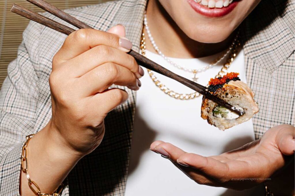 A person smiling while holding sushi with chopsticks