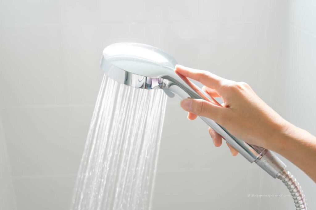 Hand holding a shower head with water running