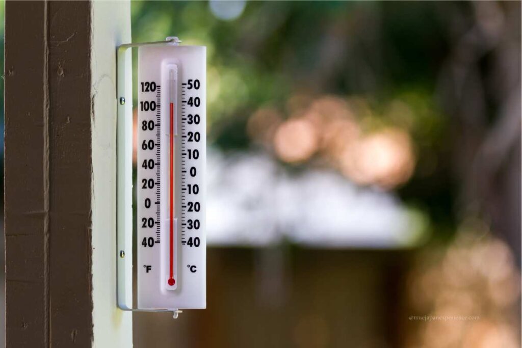 Outdoor thermometer showing high summer temperature in both Celsius and Fahrenheit.