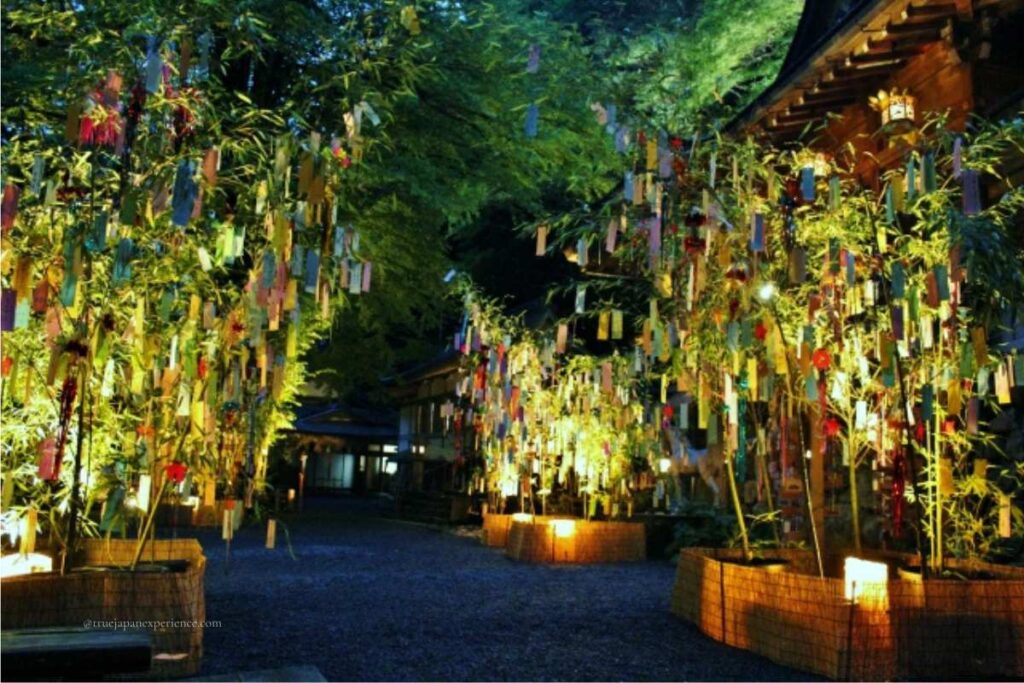 Tanabata bamboo decorations with colorful paper strips lit up at night during the summer festival at Kifune Shrine.