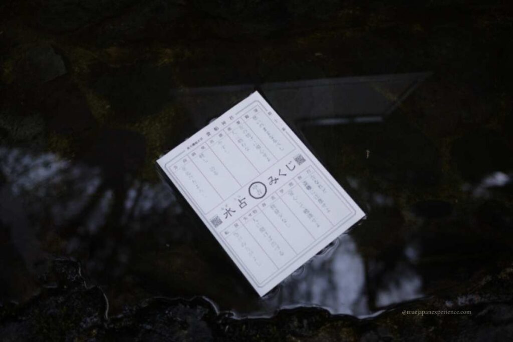A water fortune paper (Mizuhara Omikuji) floating on sacred water at Kifune Shrine, with hidden text slowly appearing.