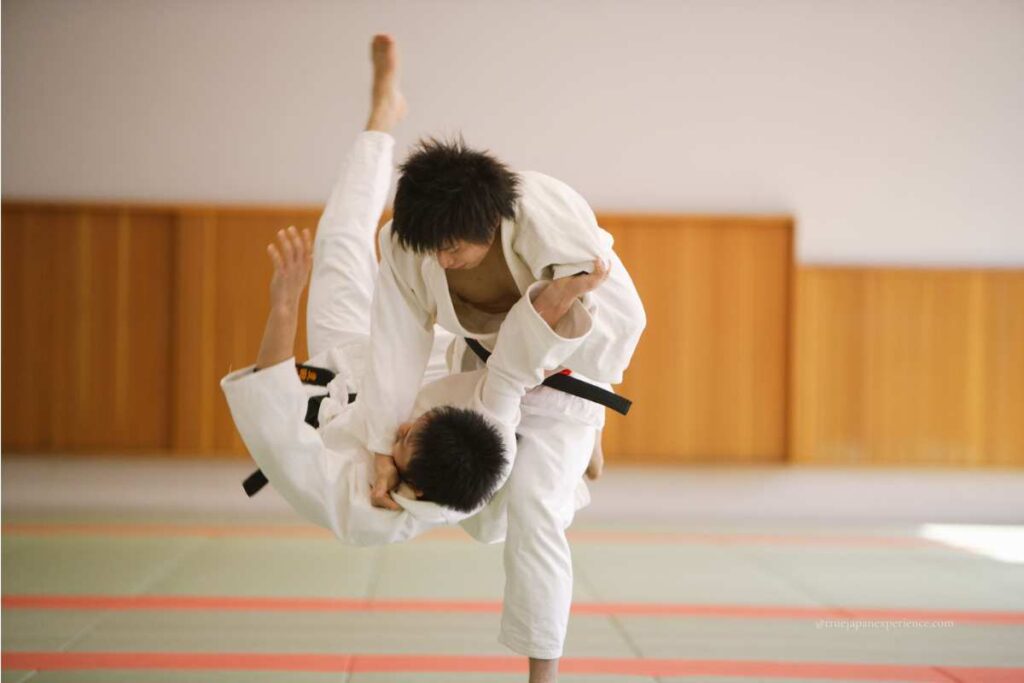 Two men practicing judo, with one throwing the other on a tatami mat.