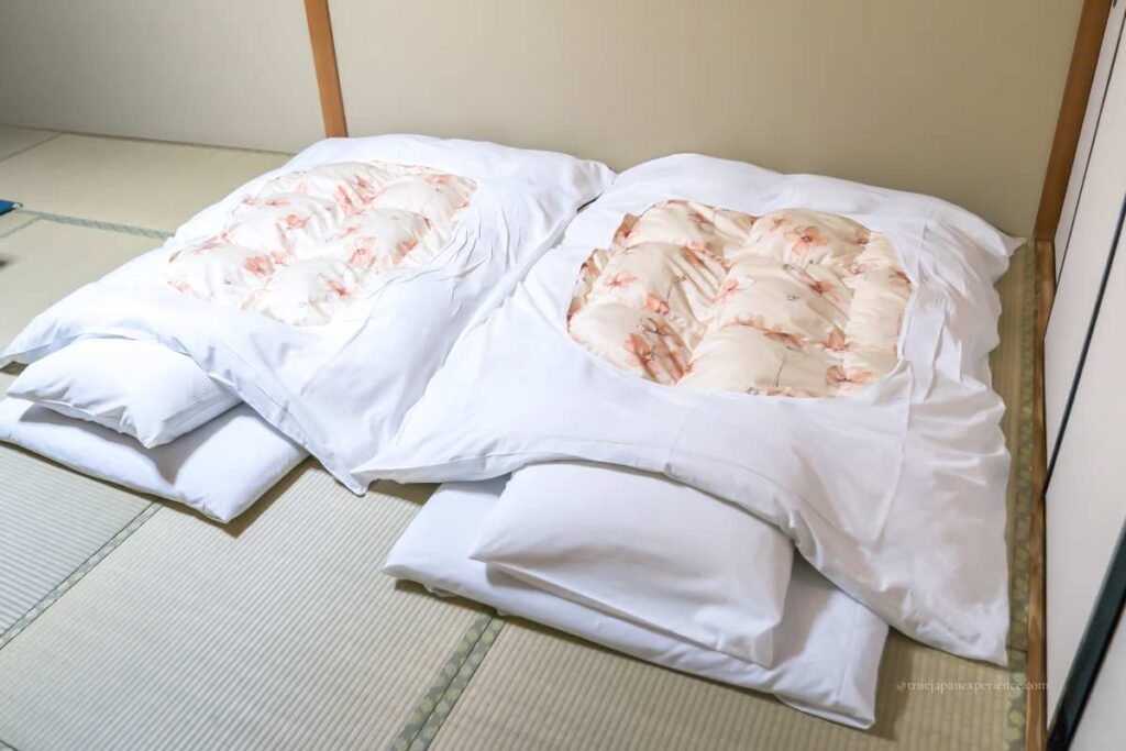 Traditional Japanese futons laid out on tatami mats in a ryokan-style room.