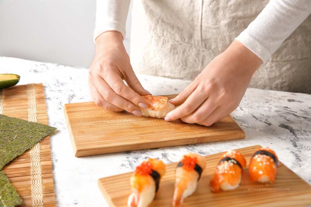 Person making sushi by hand at home.