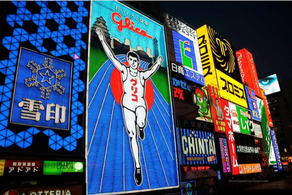 Night view of the famous Glico running man sign and colorful neon billboards in Dotonbori, Osaka.
