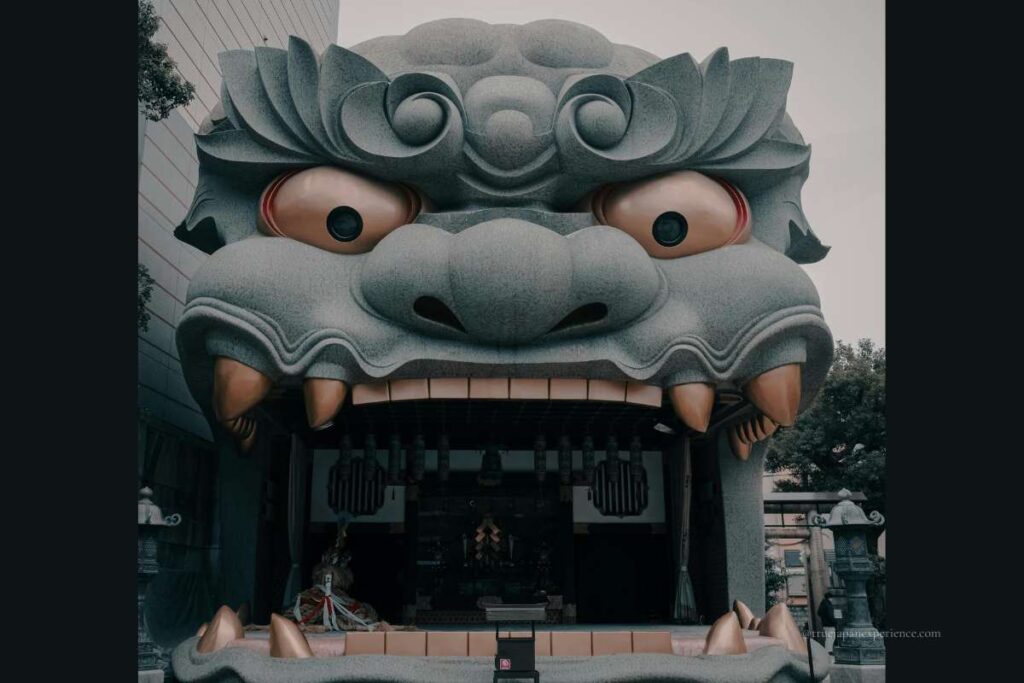 Front view of the giant lion head stage at Namba Yasaka Shrine in Osaka, showing its open mouth and worship area inside.