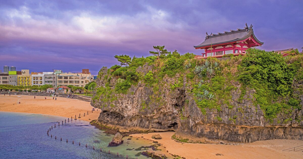 Naminoue Shrine perched on a seaside cliff in Naha, Okinawa, seen from the beach below.