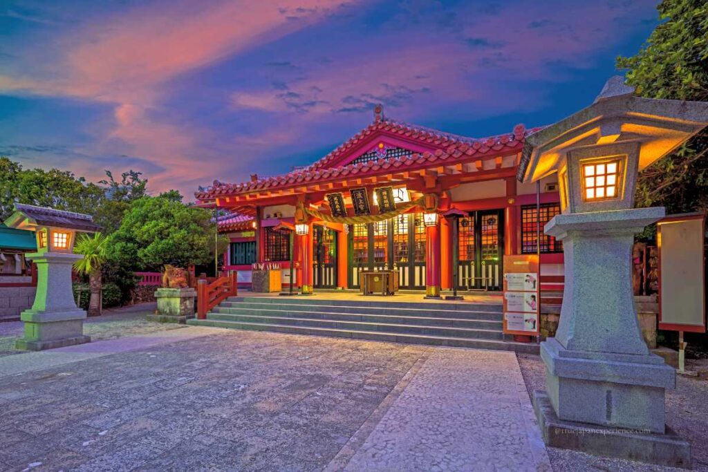 Evening view of Naminoue Shrine in Okinawa with warm lantern lights and a colorful sunset sky.
