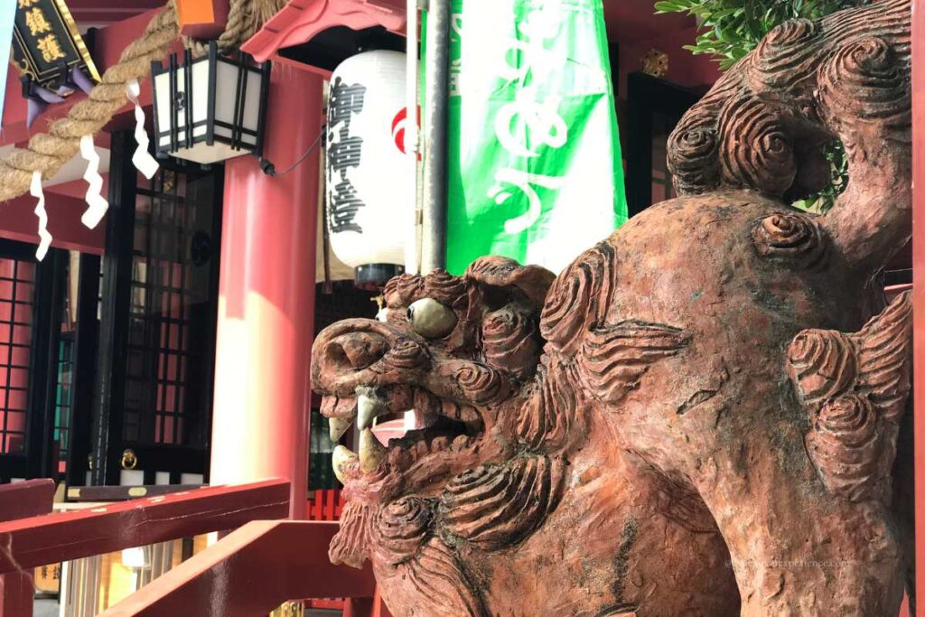 Close-up of a traditional Shisa lion-dog statue at Naminoue Shrine in Okinawa, guarding the entrance with fierce expression.