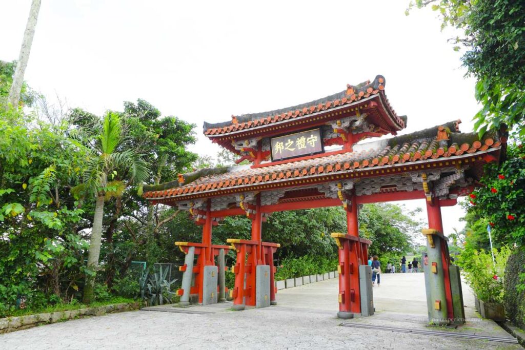 Traditional red gate at Naminoue Shrine in Okinawa, surrounded by tropical greenery.