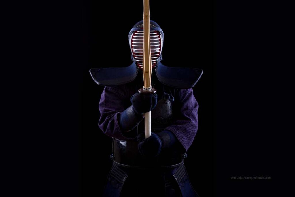Person in full kendo armor holding a bamboo sword in front stance