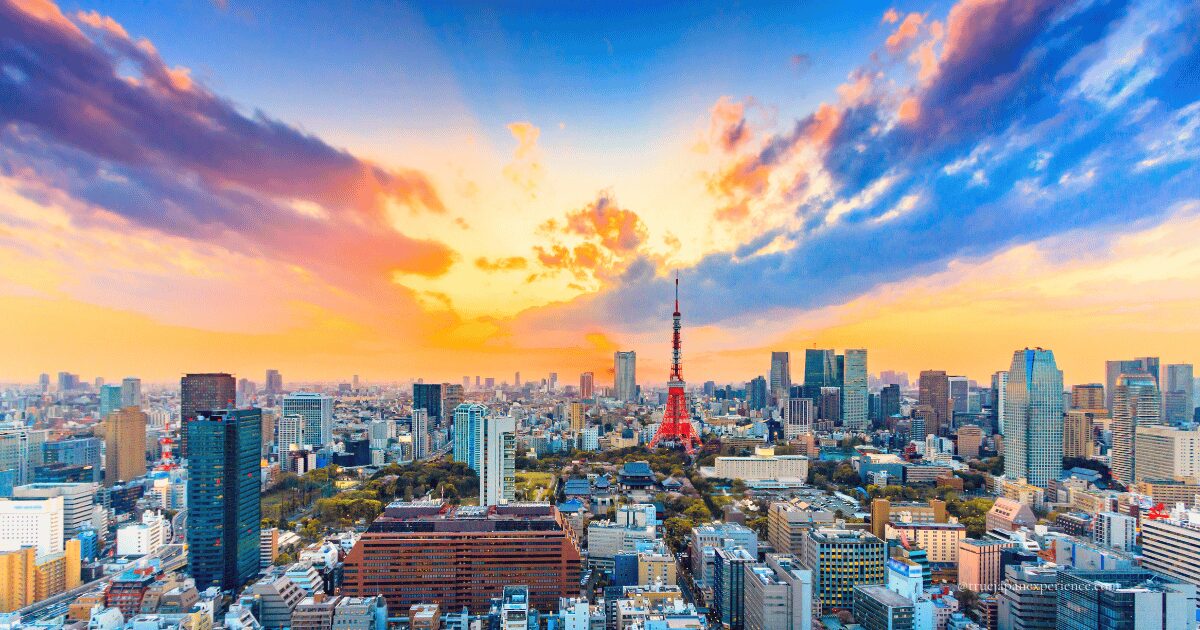 Panoramic view of central Tokyo with Tokyo Tower standing tall under a vibrant sunset sky.