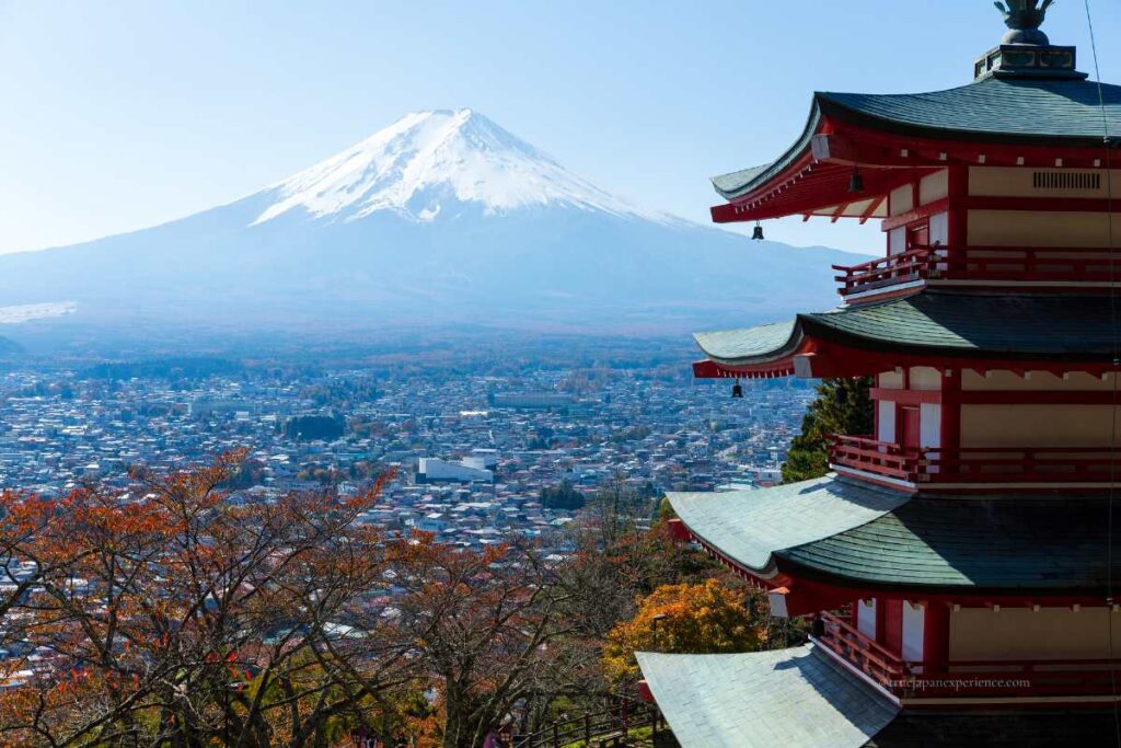 Chureito Pagoda overlooking a cityscape with Mount Fuji rising majestically in the background on a clear autumn day.