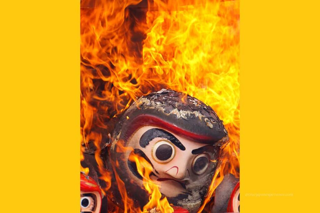 A Daruma doll burning in bright orange flames during a traditional Japanese ceremony for renewal.