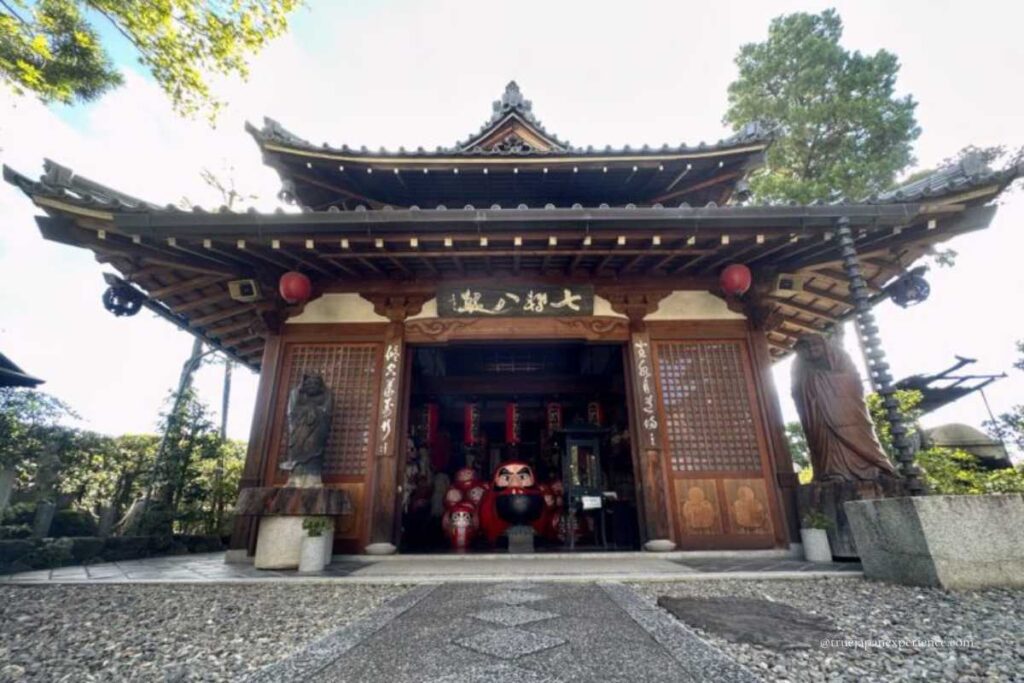 Entrance of a traditional wooden building at Darumadera Temple Kyoto with a giant red daruma doll on display