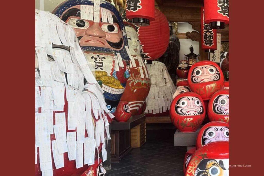 Large daruma dolls at Darumadera Temple Kyoto covered with votive slips, where visitors write wishes and paste them on the figures