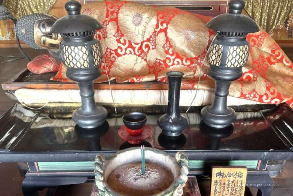 Reclining Buddha (Nehan statue) displayed with incense and offerings at Darumadera Temple Kyoto