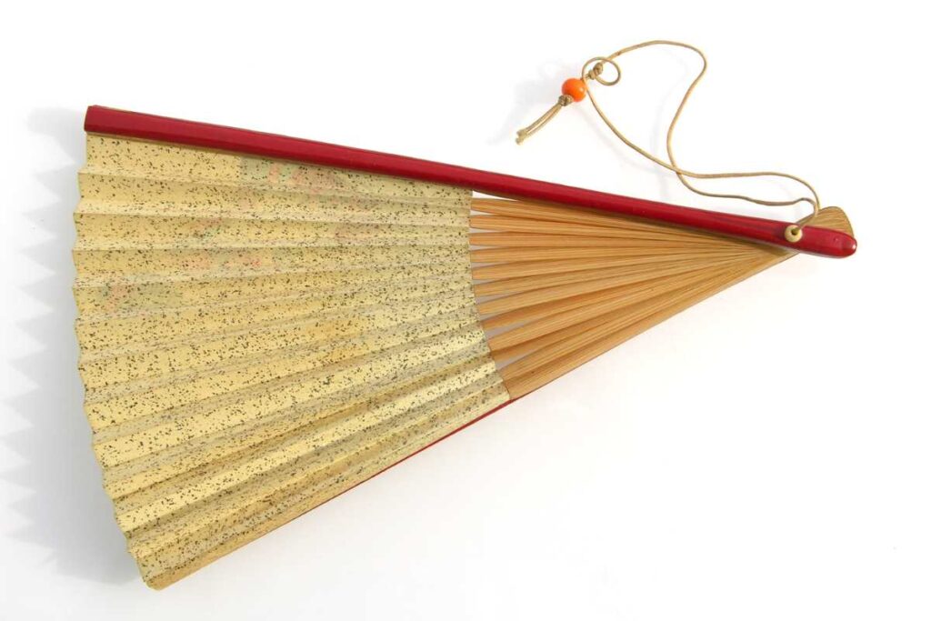 Traditional Japanese folding fan (sensu) shown half-folded, with gold paper, wooden ribs, and a red handle with cord"