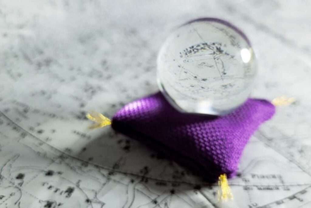 A crystal ball placed on a purple cushion over a star chart, symbolizing fortune telling.
