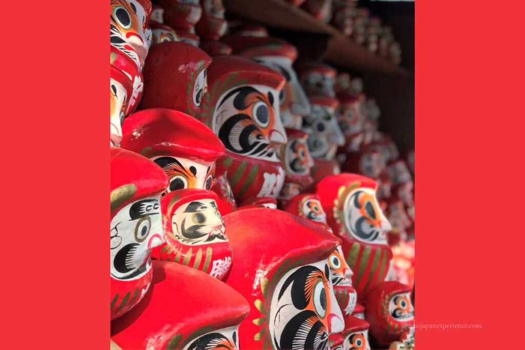 Rows of bright red daruma dolls at Katsuoji Temple, each with bold black and white painted faces, symbolizing wishes and luck.