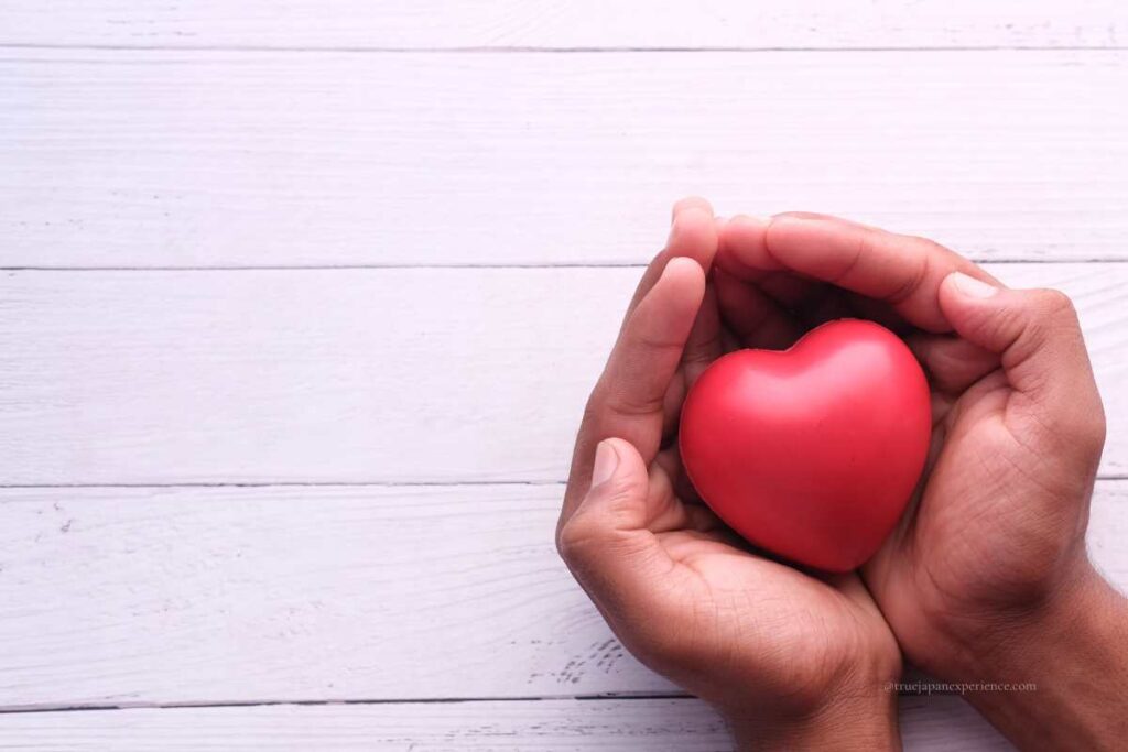 Hands gently holding a red heart, expressing kindness, care, and emotional warmth.