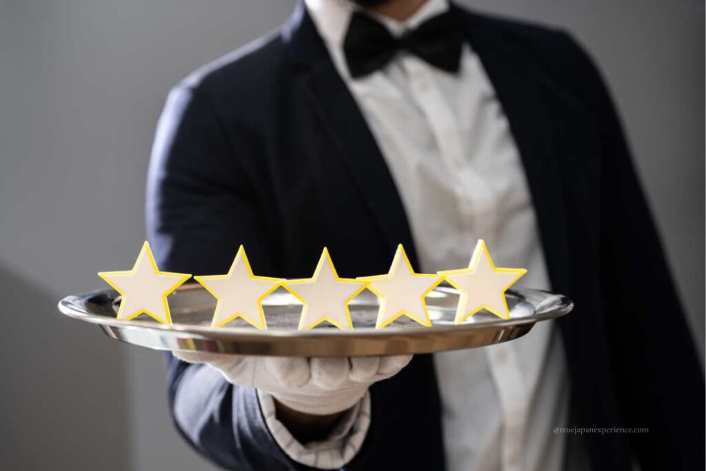 A server in formal attire presenting a silver tray with five stars, symbolizing high-quality service and expectations.