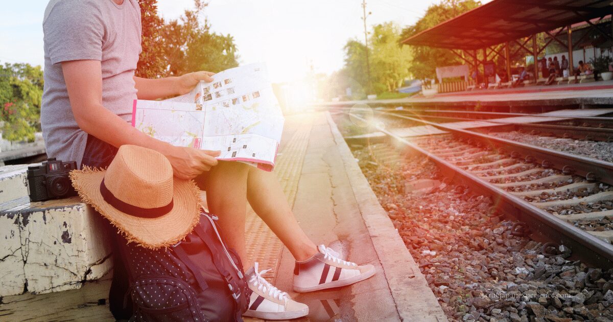 Traveler sitting on a train station platform in Japan with a map, backpack, and camera