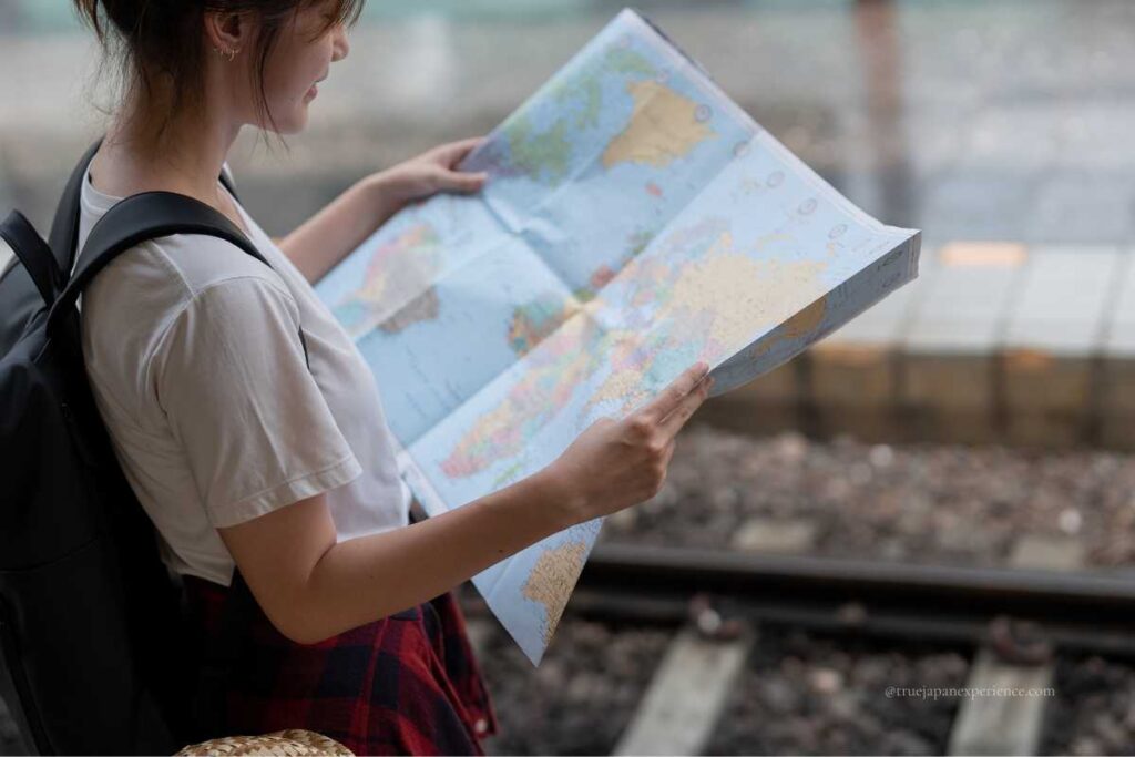 Young traveler holding a world map at a train station platform