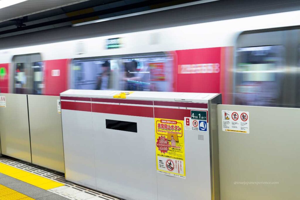 Subway platform in Japan with safety barriers and a passing train