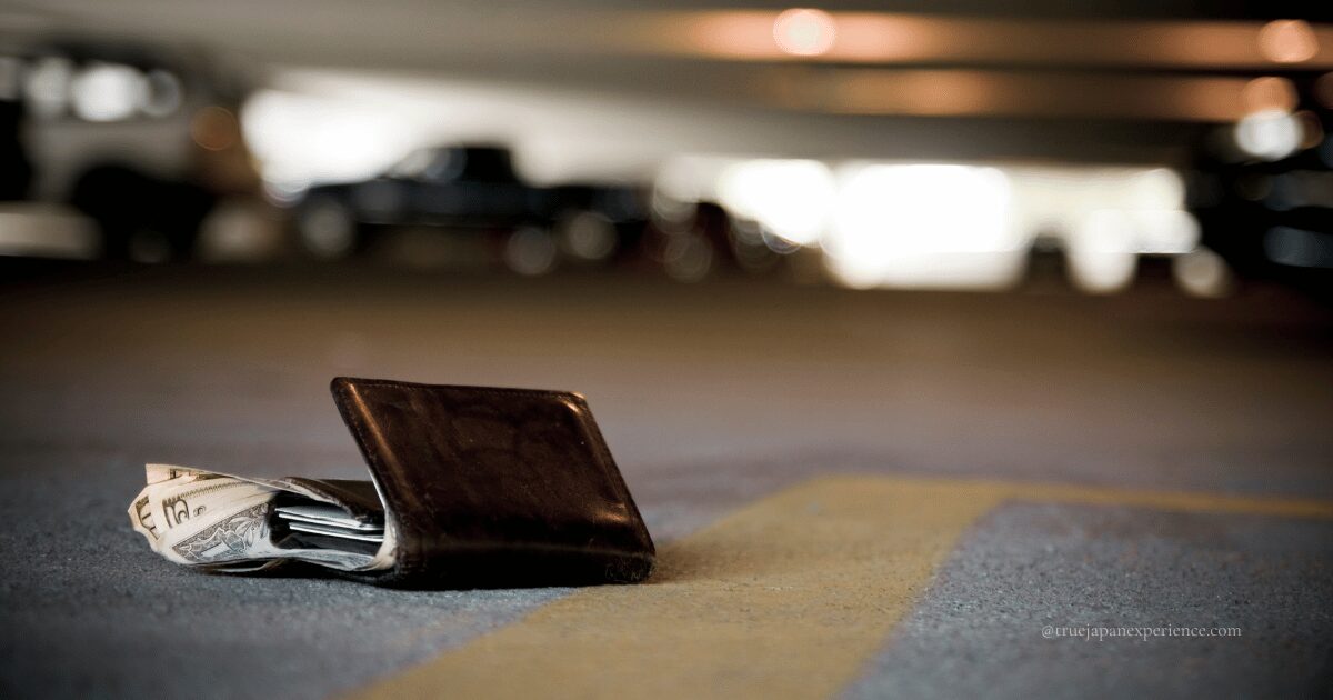A black wallet with cash inside lying on the ground in a parking area